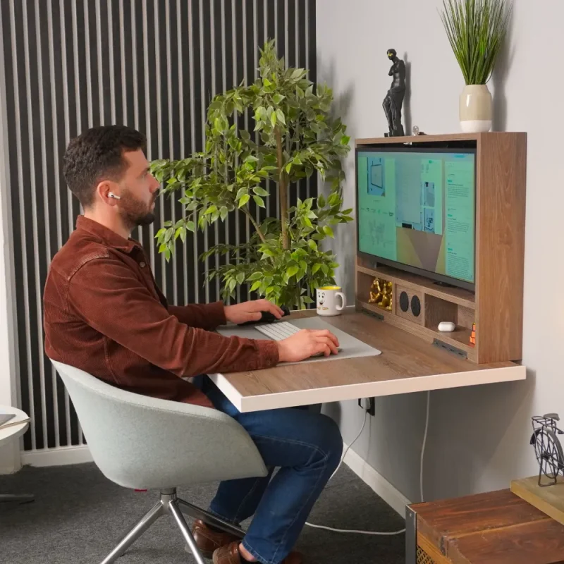 Man sat at fold up desk in a home enviroment.